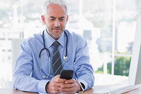 Physican Doctor Stethoscope Around Neck Looking At Mobile Phone